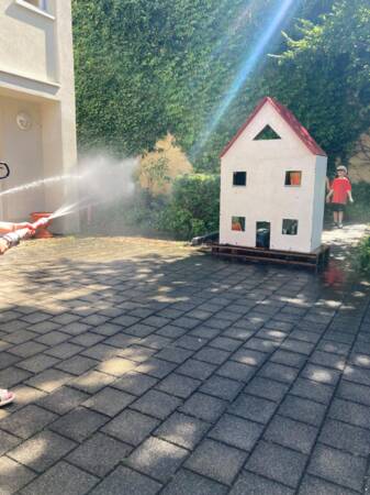 Zielübungen mit dem Löschschlauch auf ein Modellhaus.