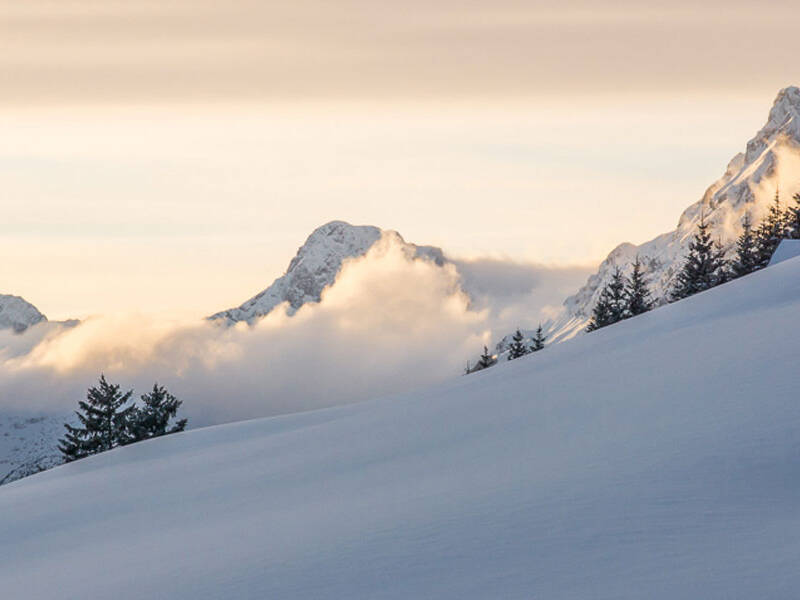 Ein schneebedeckter Hang im Sonnenaufgang.